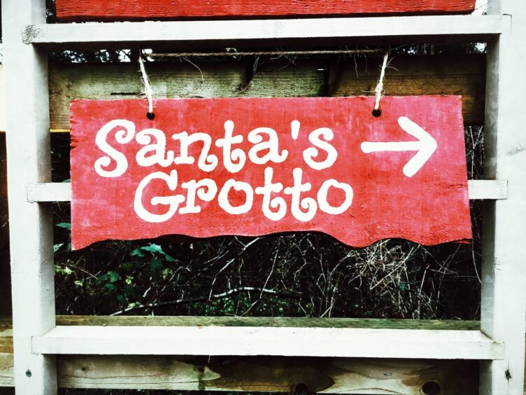 A red wooden sign for a Santa's grotto.
