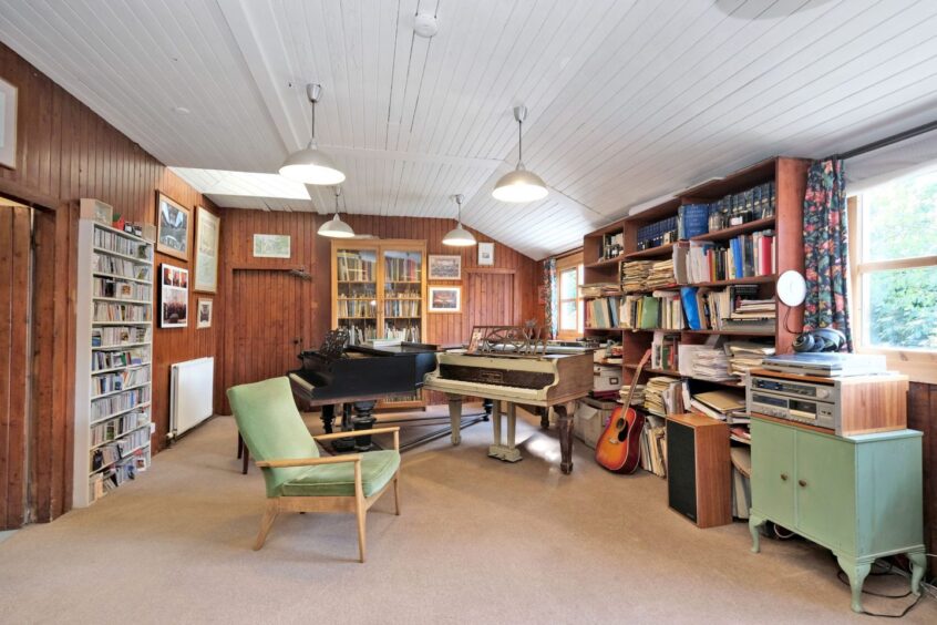 The library room in the home, featuring two grand pianos, a vinyl record player and bookcases full of books, records and cds
