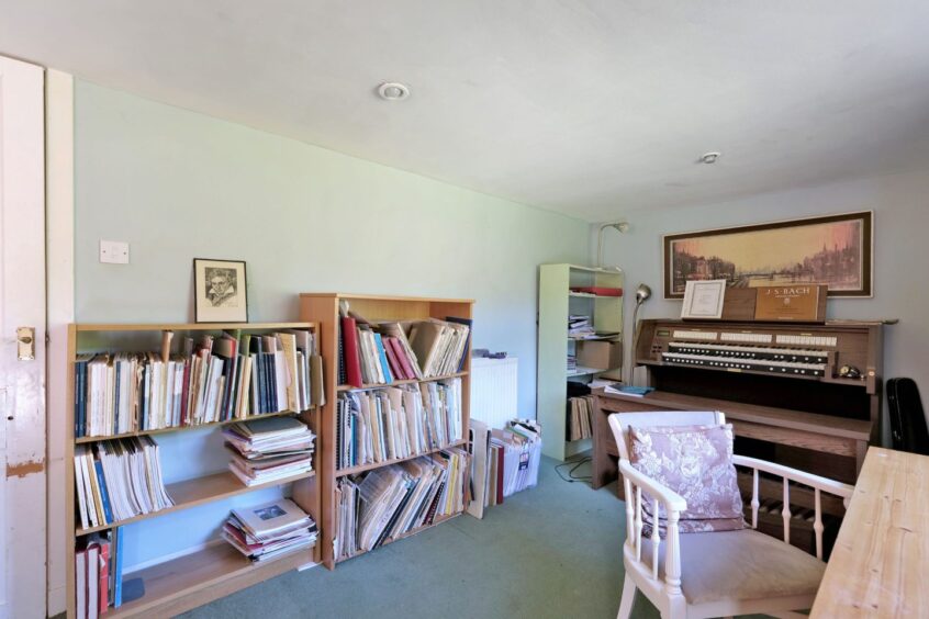 The music room with a harpsichord and bookcases full of books of sheet music