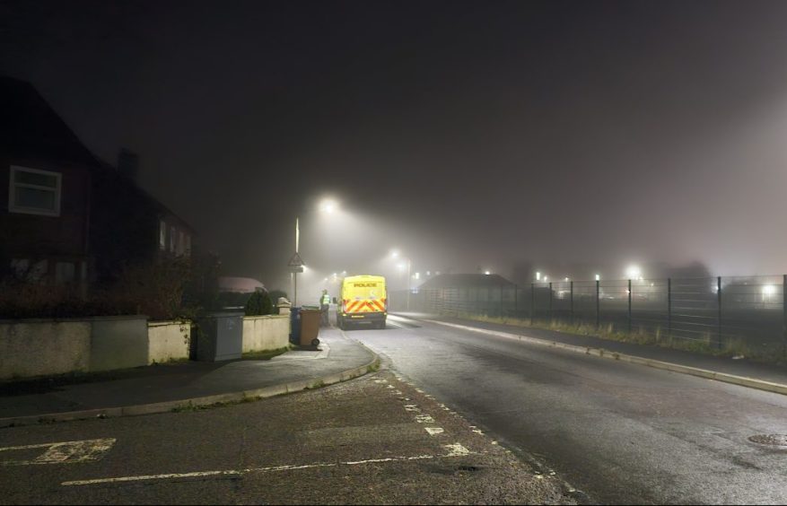A yellow police van sits outside a property on St Ninian Drive in Inverness.