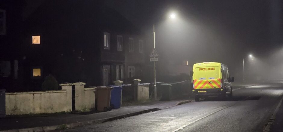 A yellow police van sits outside a property in the Dalneigh area of Inverness, where father-of-three Ross MacGillivray was found dead.