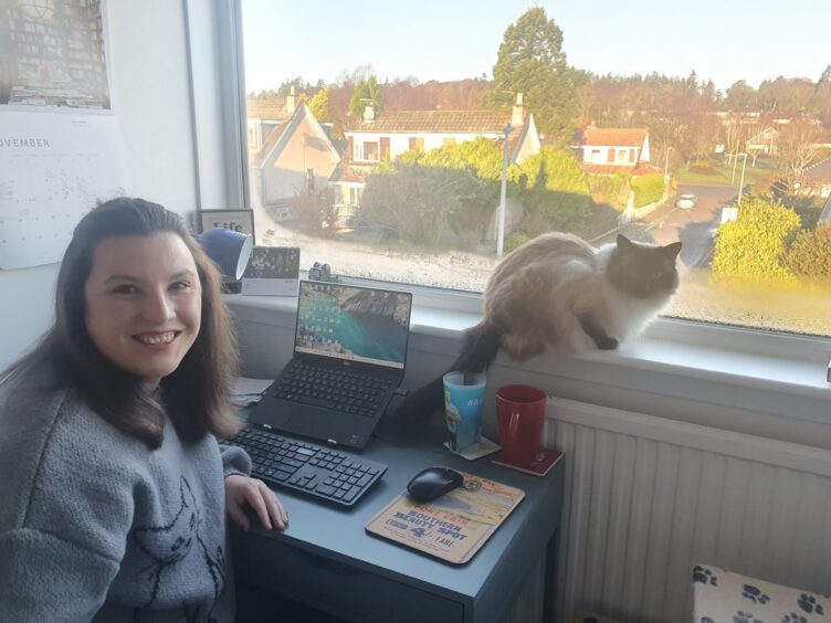 Jess Murphy in her home study with her feline companion. 