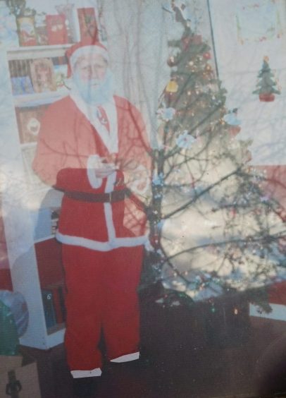 Aberdeen Santa standing next to Christmas tree in picture.