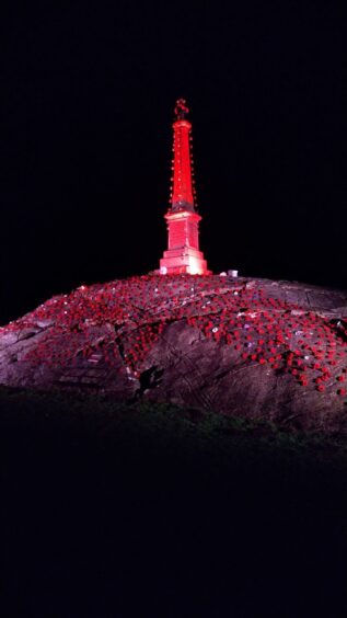 Handmade poppies cascade down from the war memorial in Gorthleck as its illuminated red for Remembrance Day.