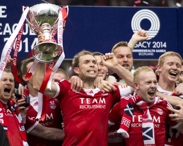 Aberdeen veteran Russell Anderson (centre) celebrates with his team-mates as he lifts the Scottish League Cup trophy in 2014. Image: SNS.