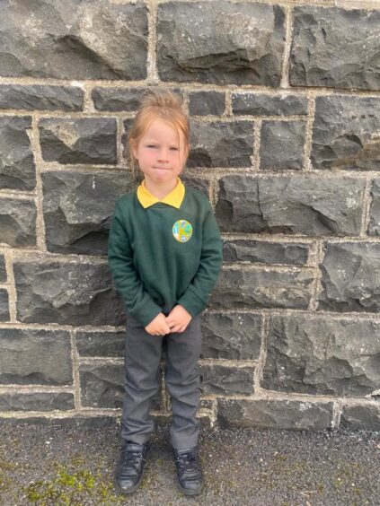 Acharacle Primary P1 pupil standing against a stone brick wall