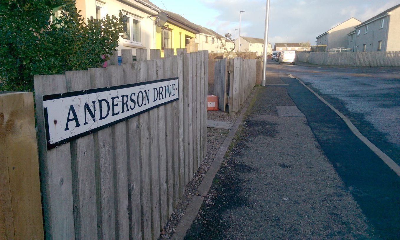 Street view of Anderson Drive sign and road behind. 