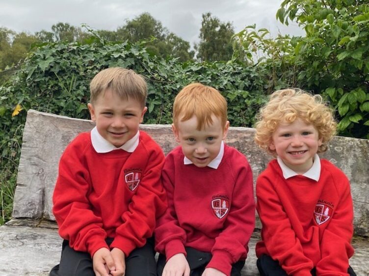 Balnain Primary School's three P1 pupils sitting on a wooden bench