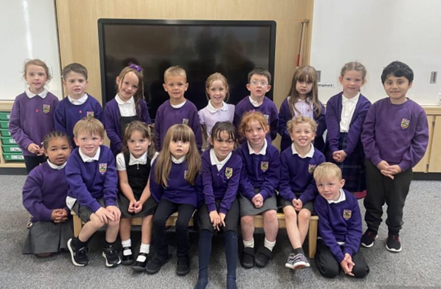 Class P1M at Ben Wyvis Primary in two rows in the classroom