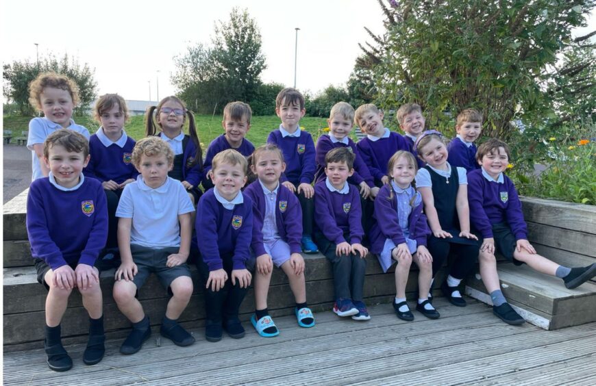 Class P1C sitting in two rows outside Ben Wyvis Primary School