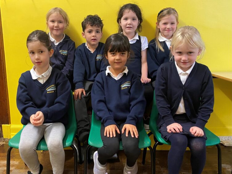 First class of 2023 at Bonar Bridge Primary School in the highlands and islands in two rows in front of a bright yellow wall