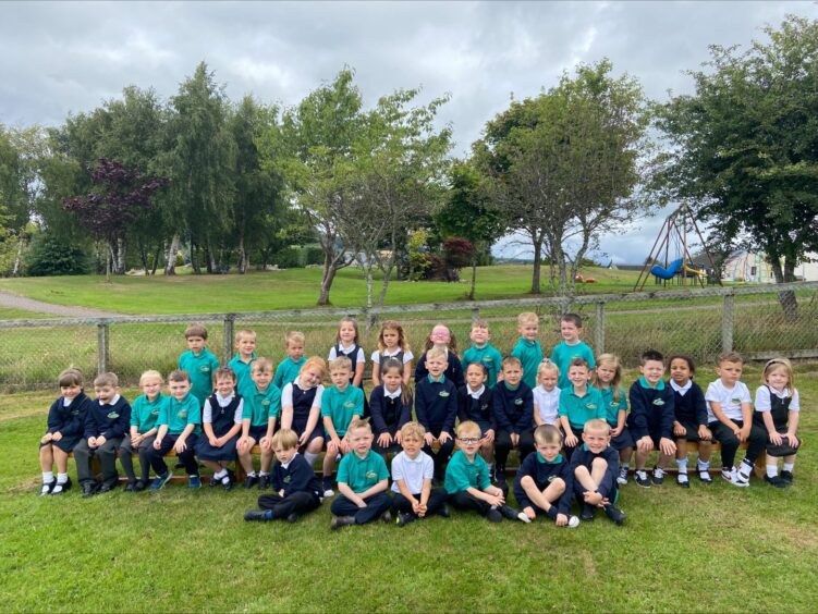 Bridgend Primary School's P1 class sitting in rows outside on the grass