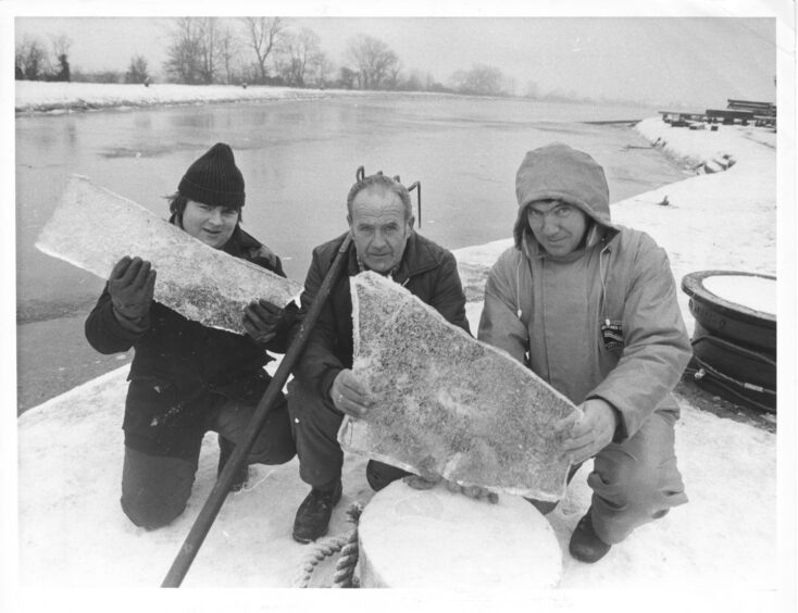 Three Caledonian Canal workers hold up thick sheets of ice taken when clearing the locks in 1984.