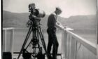 an old black and white photo of a man with a camera watching loch ness