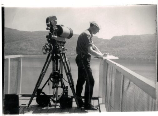 an old black and white photo of a man with a camera watching loch ness