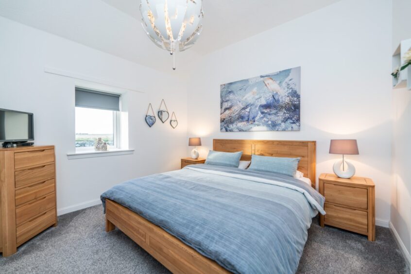 The bedroom which has wooden and light blue tones throughout