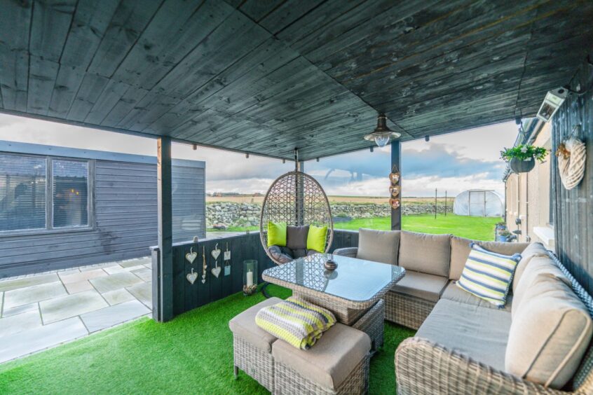The outdoor space, which has a patio sofa, hanging chair and a coffee table