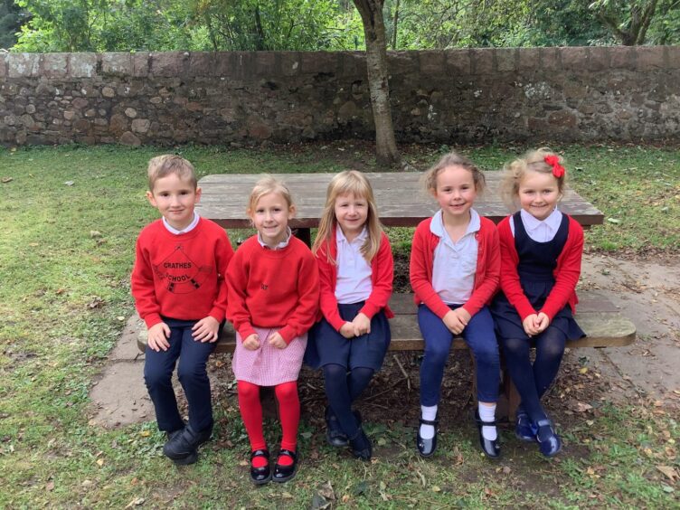 Aberdeenshire's Crathes Primary School's first class of 2023 sitting on a picnic bench on the school grounds