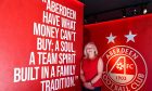Elaine Farquharson-Black in front of a wall with the Aberdeen FC badge on it