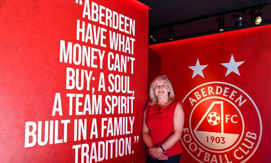 Elaine Farquharson-Black in front of a wall with the Aberdeen FC badge on it