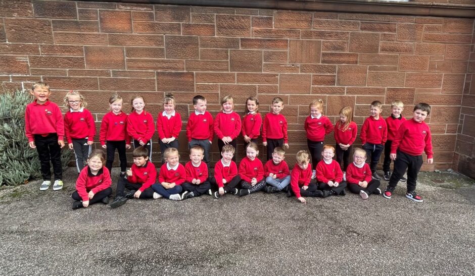 First class of 2023 at Dalintober Primary School in the highlands and islands in two rows outside the school in front of a brick wall