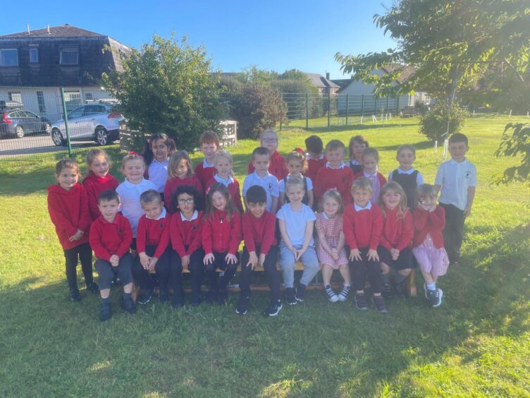 Dalneigh Primary School pupils in three rows on the grass outside the school
