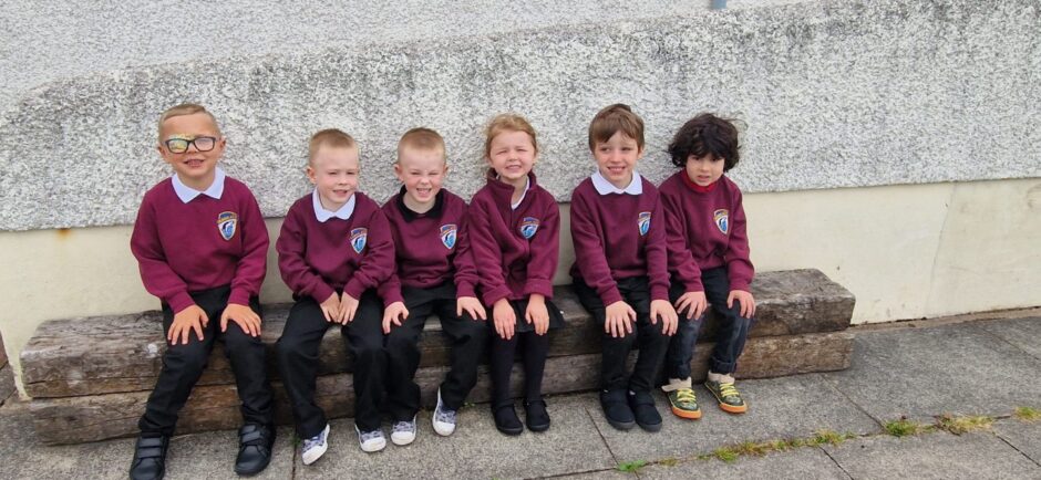 First class of 2023 at Dunbeath Primary School in the highlands and islands sitting on a bench outside the school