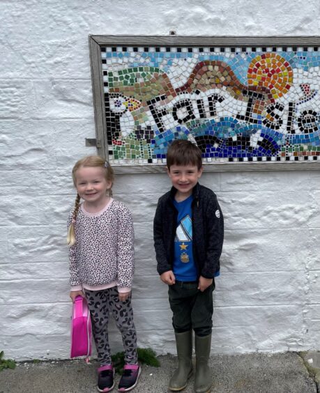 Fair Isle Primary School pupils with a mosaic tiled sign above them