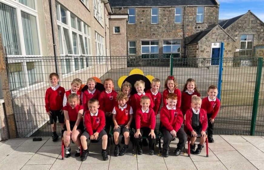 First class of 2023 at Inverallochy School in aberdeenshire sitting in two rows outside the school building