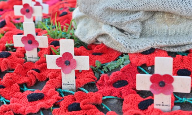 Red poppies and wooden crosses lay on the ground as part of remembrance day displays.