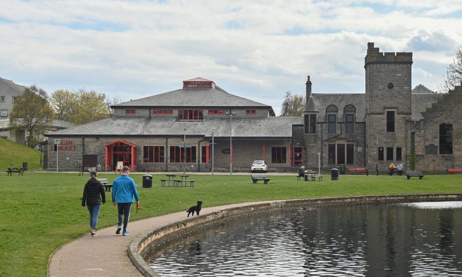 Two people walking by pond in Cooper Park.