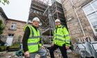 Two men in high-viz jackets with construction on new care home lift behind.