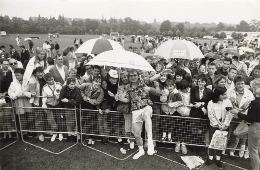 Adrian John shelters from the rain with help from fans. Supplied by DCT Archives.