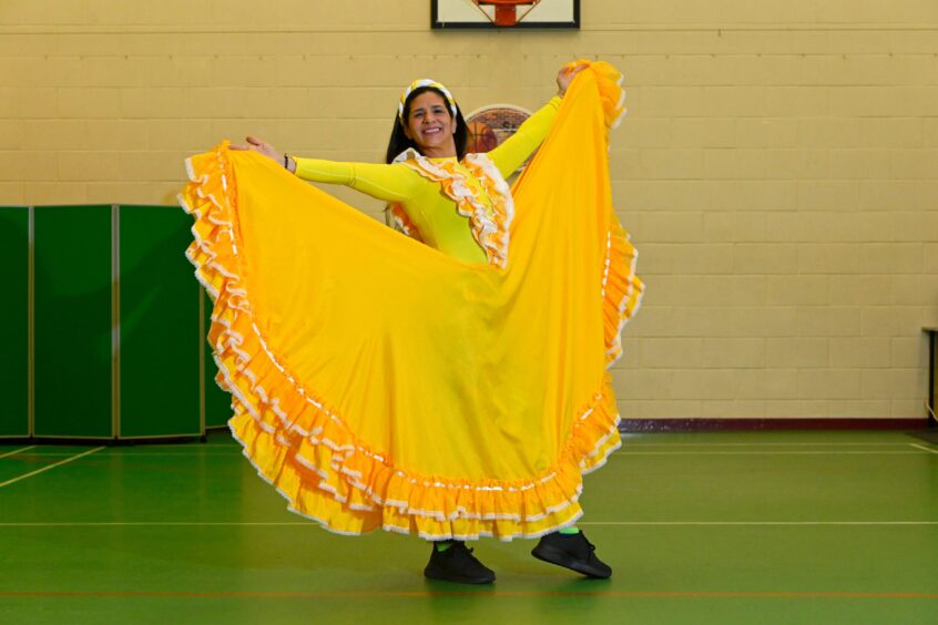 Mailen Vásquez de Palmero in a fitness hall wearing a bright sunshine-yellow dress with white frills
