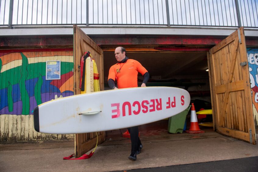 Adam Rofe from Aberdeen Surf Life Saving Club carrying a surd board from their base at Aberdeen beach.