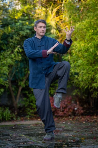 Matthew Knight, who has Aberdeen tai chi classes, with his arms out and one leg in the air