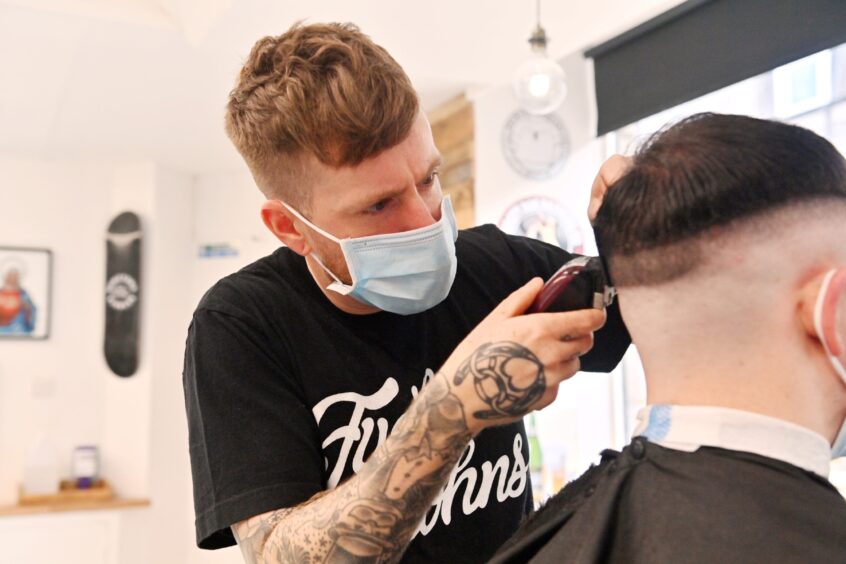 Roo MacKinnon shaving someone's head in the barber shop Hometown Barbers in Aberdeen. 