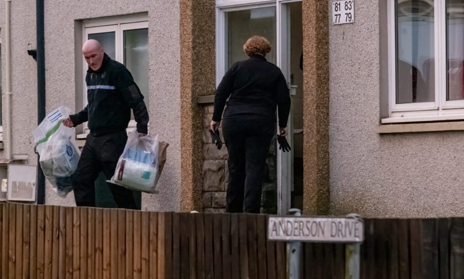 Police officers removing bags of evidence from home. 