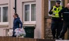 Police officer removing bags of evidence from Anderson Drive flats.