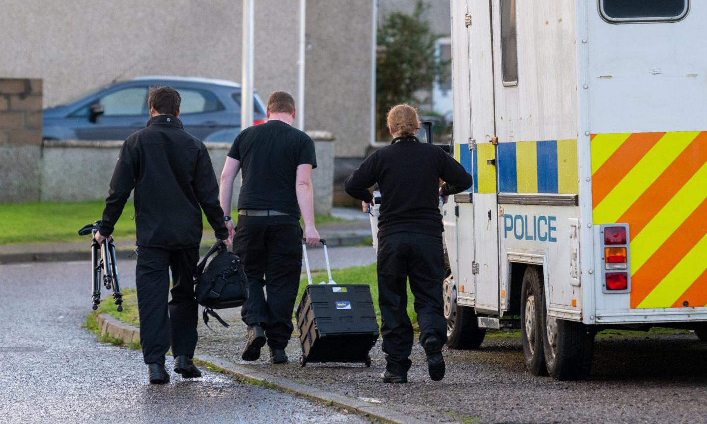 Police officers with a box and tripod on Anderson Drive. 