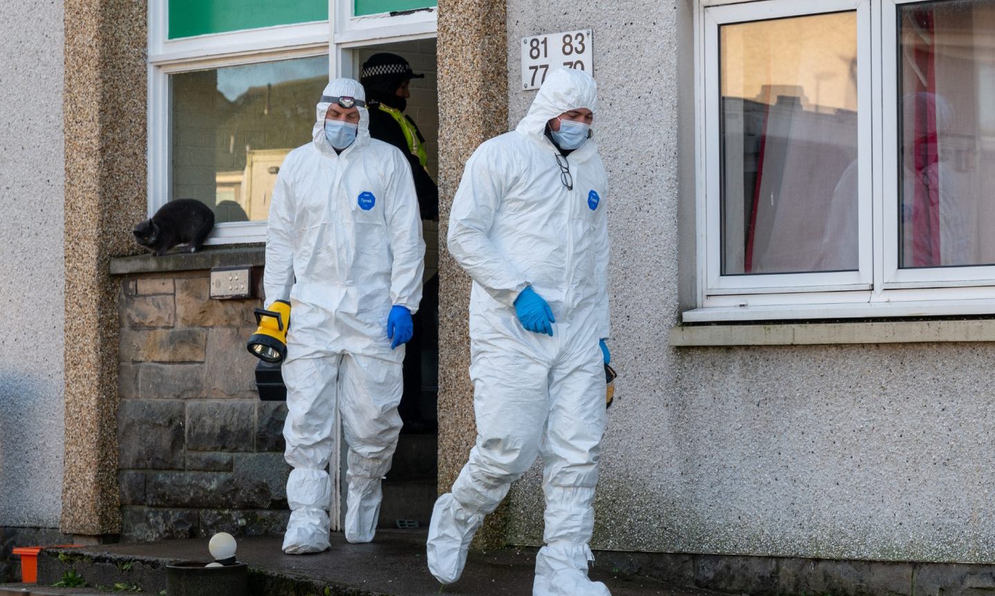 Forensic police officers coming out of flats. 