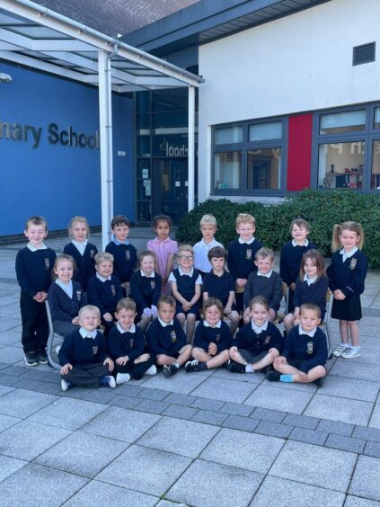 Class P1M at Keith Primary lined up in three rows in front of the school entrance