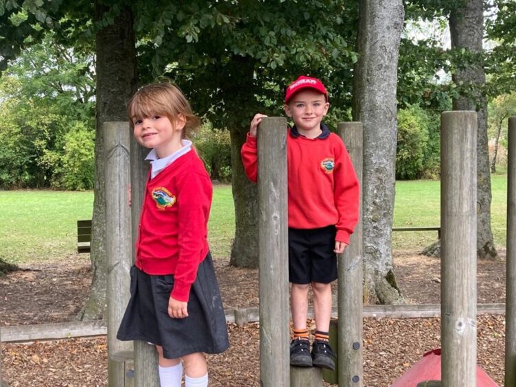 Two primary 1 pupils from King Edward School standing on playground equipment