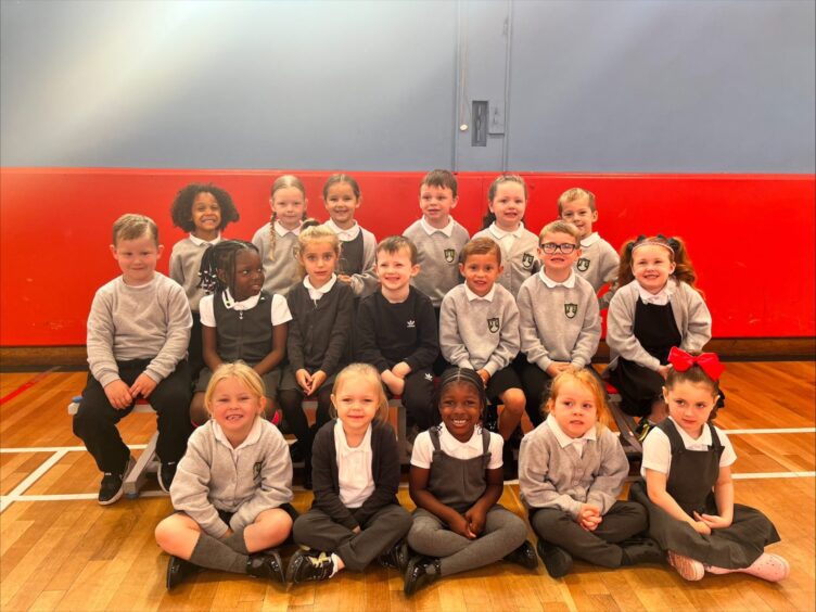 Class P1K at Kirkhill Primary School lined in three rows in the PE hall