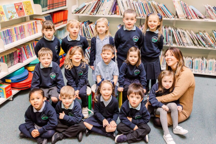 Aberdeenshire primary school, Lairhillock School's first class of 2023 in three short rows in the school library with Mrs Gill.