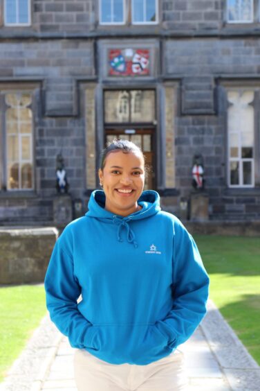 Student President of Aberdeen University Vanessa Mabonso Nzolo in a blue hoodie smiling at the camera on campus