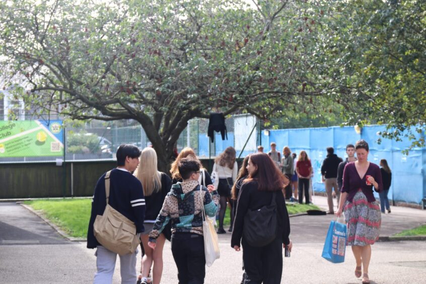 Students walking around Aberdeen University campus in the sunshine. 