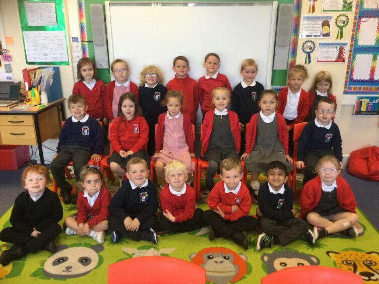 Mintlaw Primary School pupils in three rows at the front of their class room, the whiteboard behind them