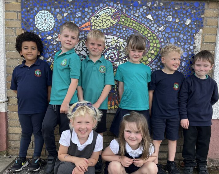 Munlochy Primary School pupils with a mosaic tile mural behind them