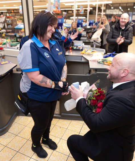 Mike Durrant gets down on one knee to propose to Lynne Fuller at the checkouts at an Aldi in Inverness.